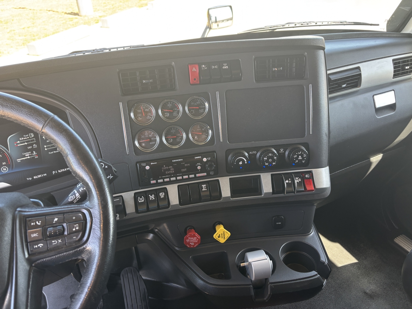 Kenworth T680 interior dashboard view showing multiple gauges, center console, and steering wheel. Visible controls, vents, and switches.