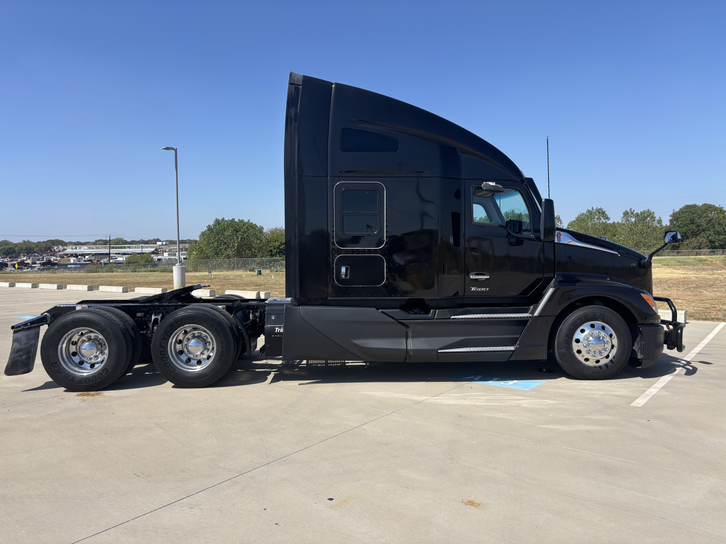 Kenworth T680 tractor in profile view, black exterior, sleeper cab, six-wheel configuration, side view shows cab and chassis with dual rear axles.