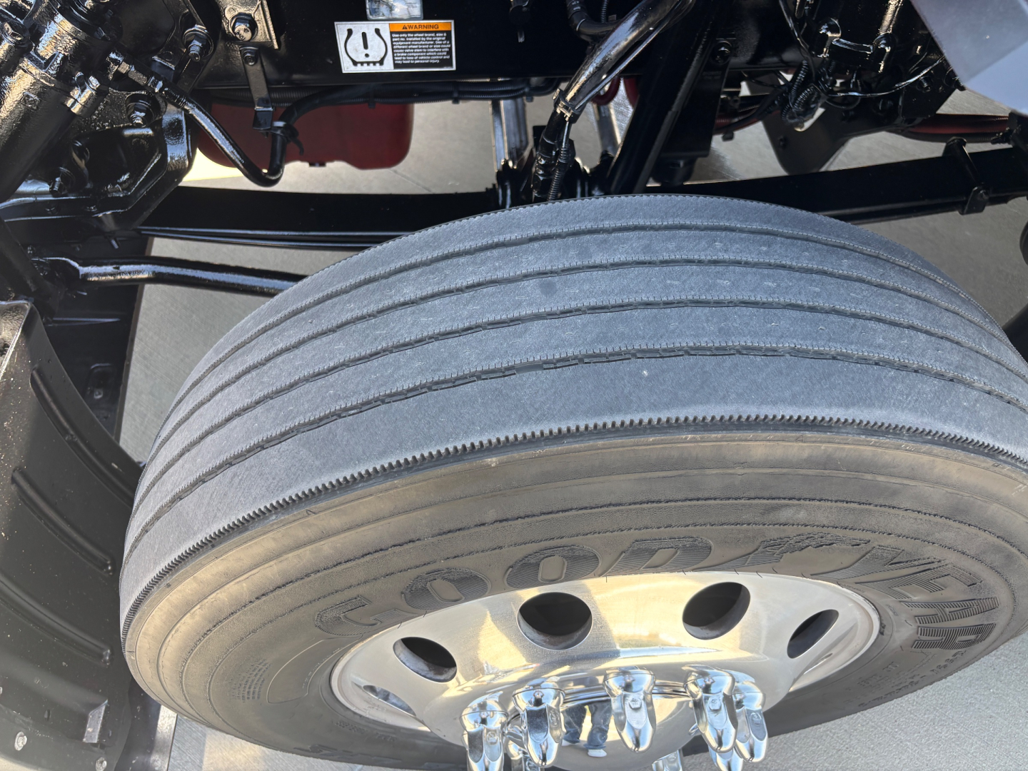 Kenworth T680 truck wheel and tire view showing front dual rear wheel area, with Goodyear tire visible and parts of suspension/frame in background.
