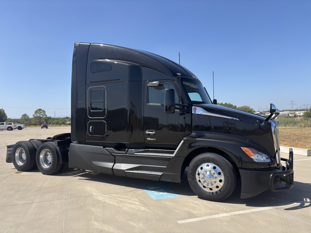 Kenworth T680 semi-truck side profile, black cab, chrome wheels, spare fuel tanks visible, no visible text on side.
