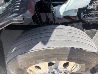 Kenworth T680 truck front wheel well detail showing large tire and rim, part of undercarriage area