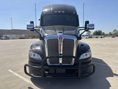 Kenworth T680 truck front view with grille guard and dual headlights in a parking lot showing chrome grille and black bumper guard.