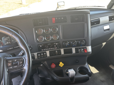 Kenworth T680 interior dashboard view showing multiple gauges, center console, and steering wheel. Visible controls, vents, and switches.