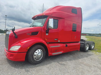 Peterbilt 579 truck, red cab, front left view, chrome mirrors, dual rear wheels, no trailer attached.