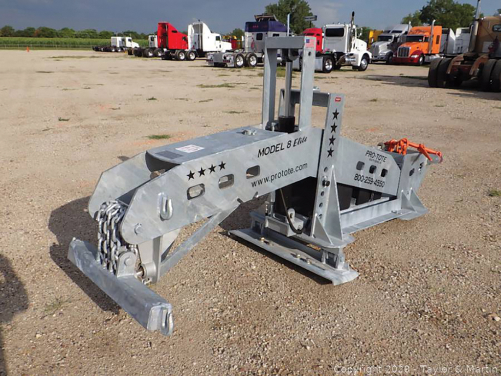 Pro-Tote 8 Elite hydraulic fifth wheel wrecker by Pro-Tote in a gravel lot, metal gray frame with chains and towing hitch, model 8 Elite markings and star decals.