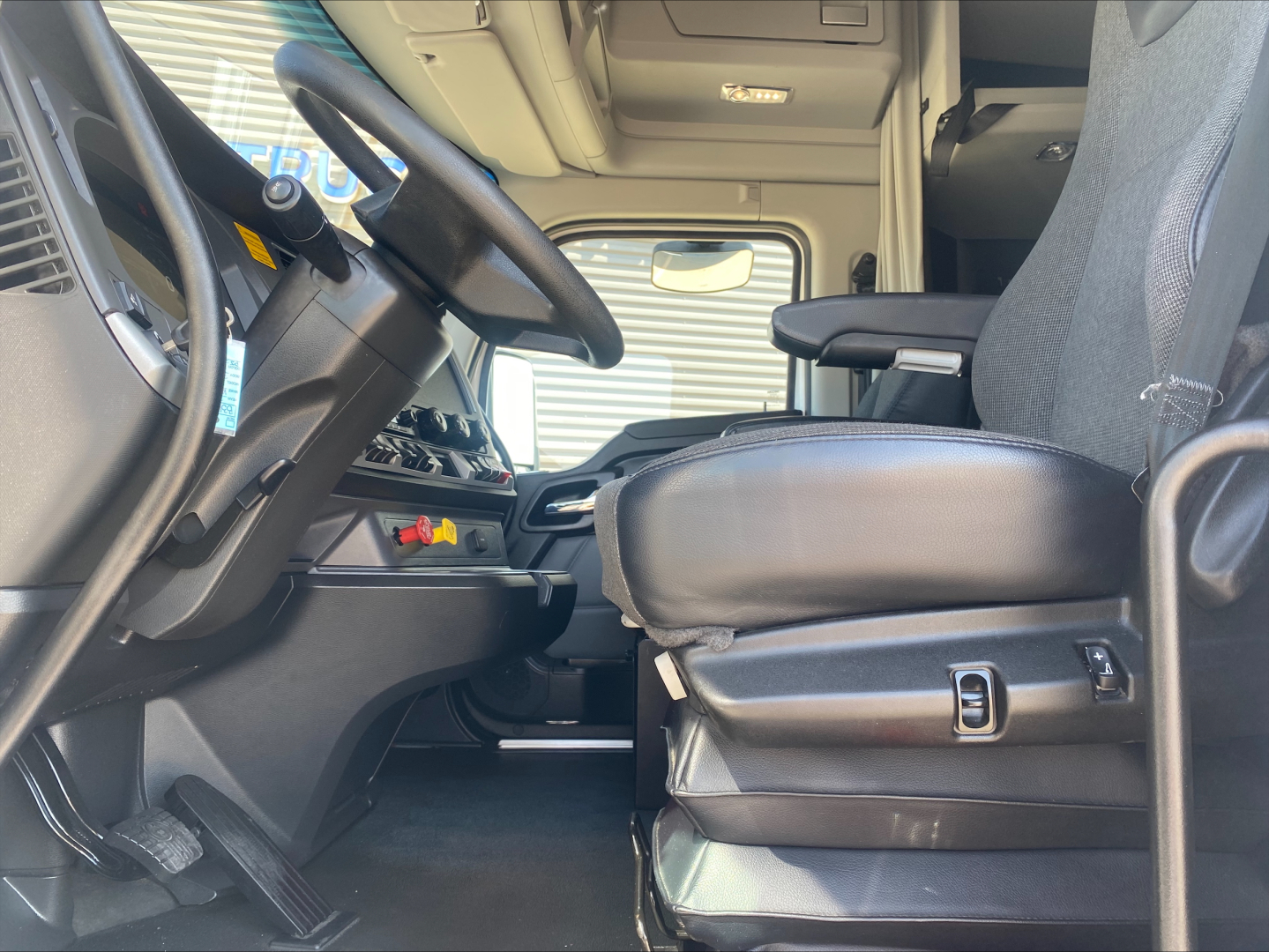 Kenworth T680 truck interior showing driver's seat and dashboard with steering wheel and controls.