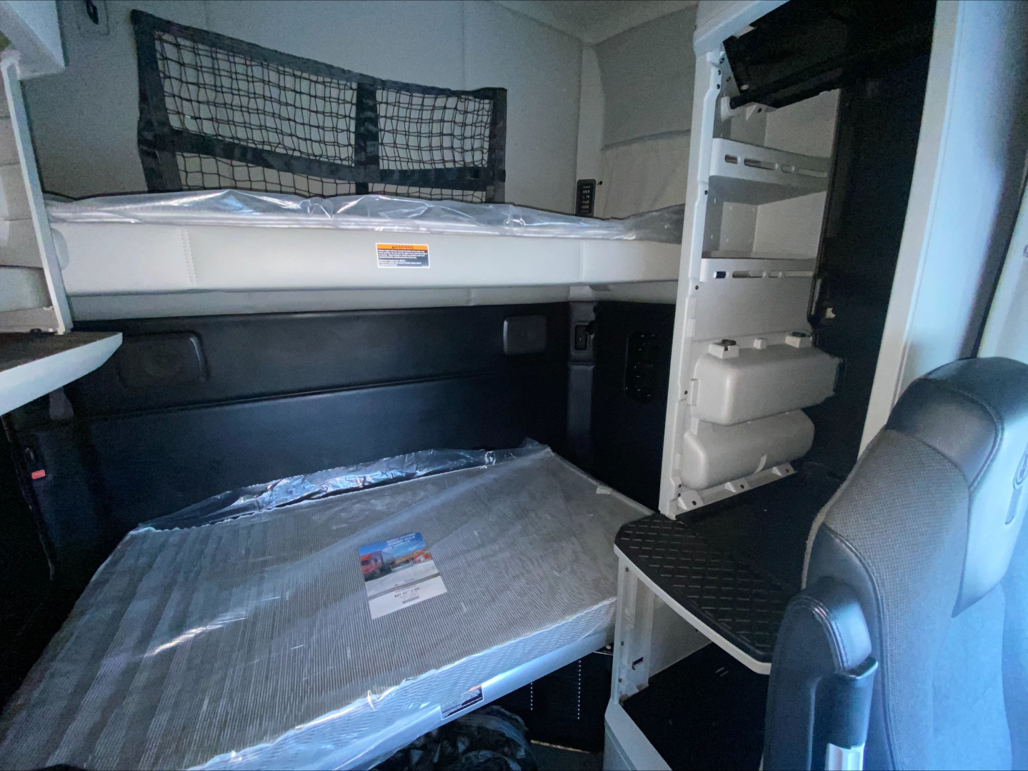 Kenworth T680 sleeper cab interior with upper and lower bunks in a truck cabin.