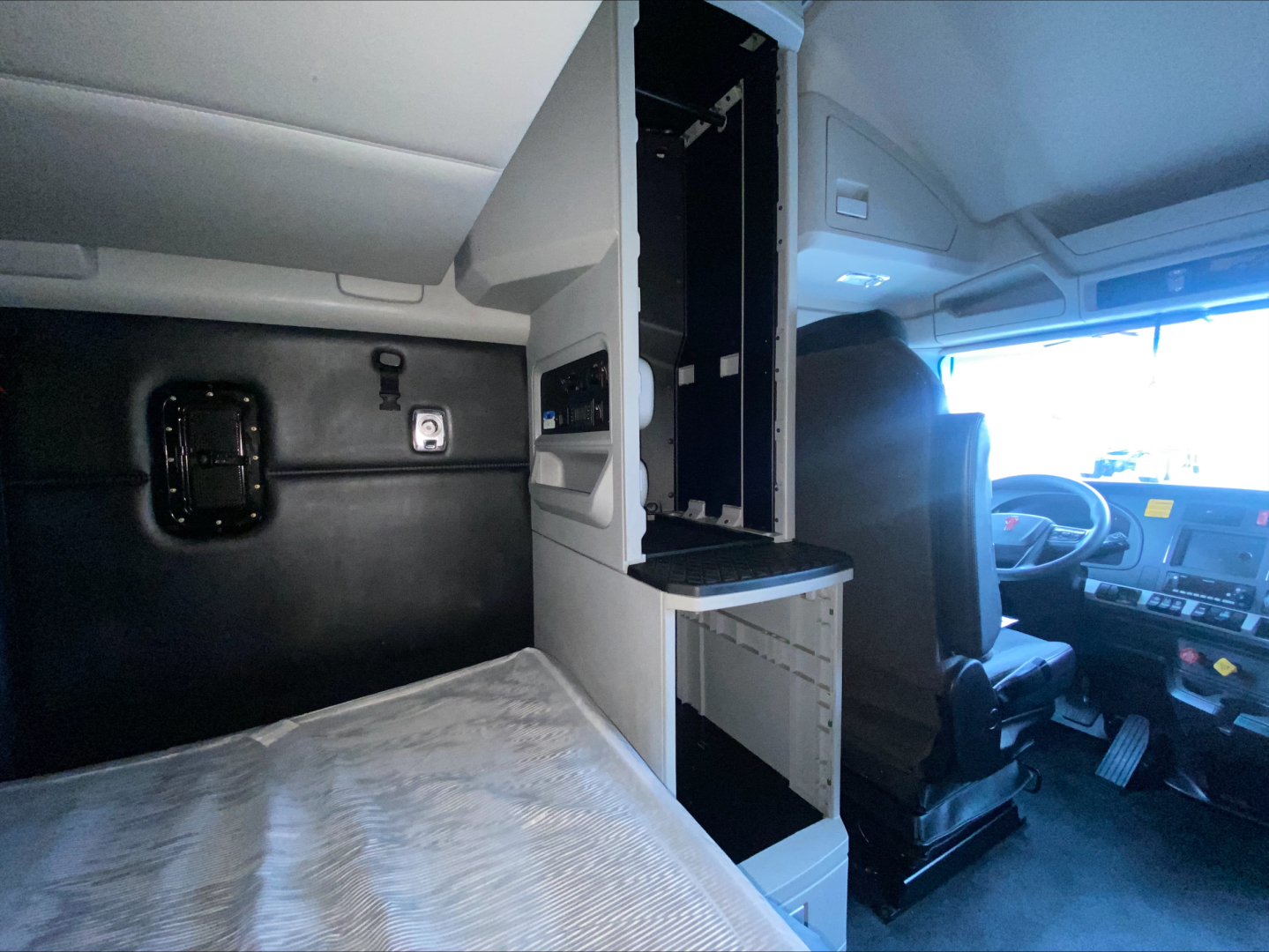 Kenworth T680 cab interior showing sleeper area with storage compartments and driver seat, dashboard visible