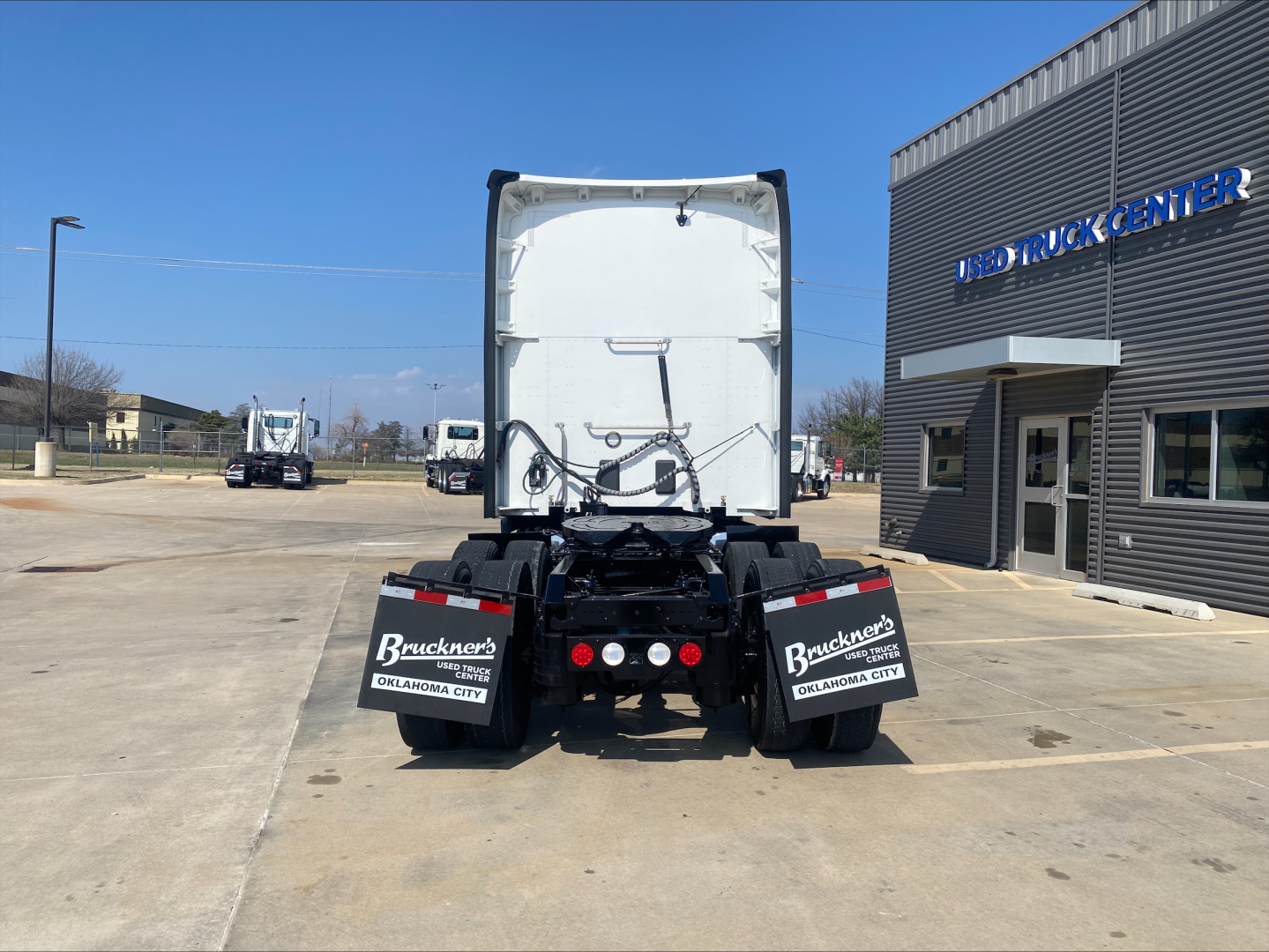 Kenworth T680 rear view showing fifth-wheel, mud flaps, and bumper lights at a used truck center yard.