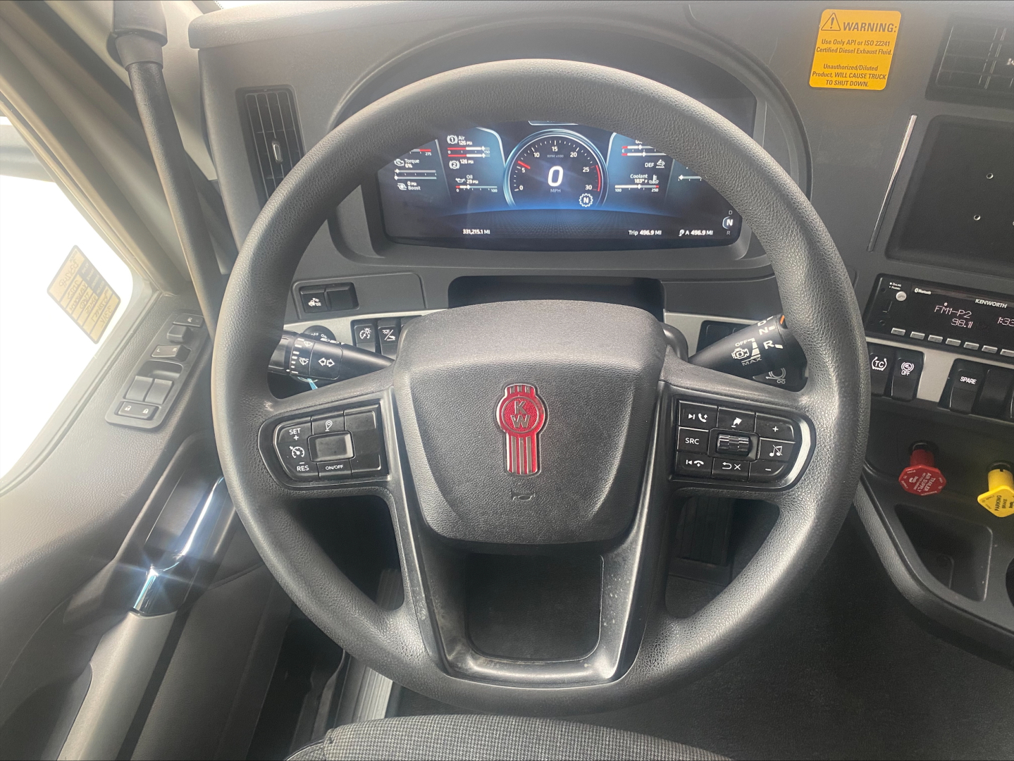 Steering wheel view inside a 2023 Kenworth T680 cab showing digital instrument cluster and steering controls.