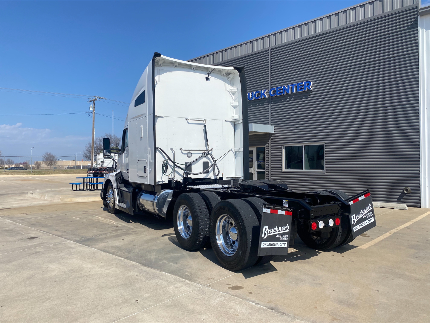 Kenworth T680 truck tractor rear view showing triple axle rear with black chassis and white sleeper cab.