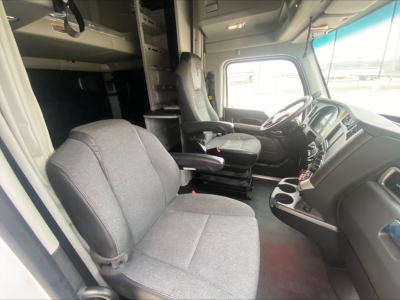 Kenworth T680 truck cab interior showing driver and passenger seats, steering wheel, and dashboard from the cabin doorway.