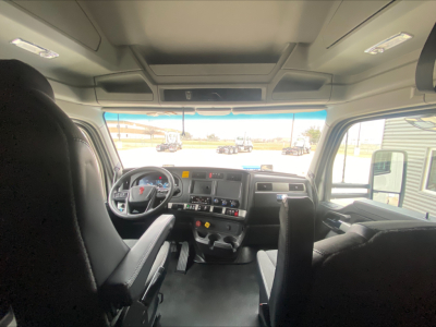Kenworth T680 truck interior cab view from rear seats showing steering wheel, dashboard, and front windshield.