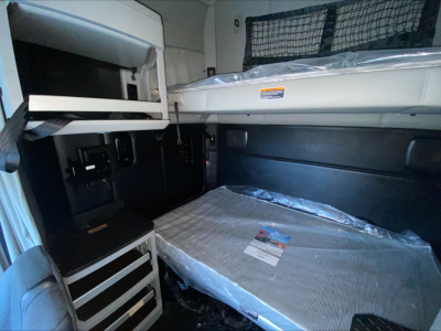 Kenworth T680 sleeper cab interior showing bunk bed area and upper storage cabinet.