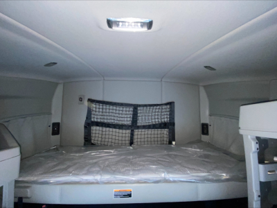 Kenworth T680 sleeper cab interior rear cargo area with a netted barrier and overhead cabin light.