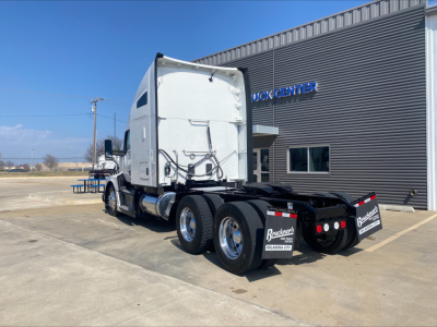 Kenworth T680 truck tractor rear view showing triple axle rear with black chassis and white sleeper cab.