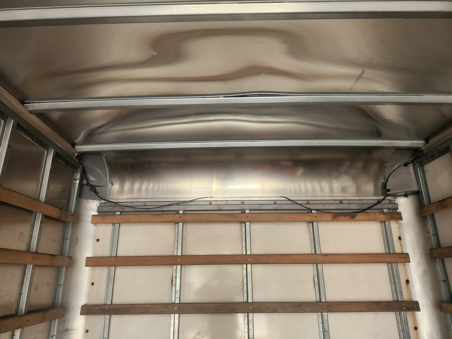 Interior of a box truck cargo area with wooden side rails and metal framing, empty cargo space.