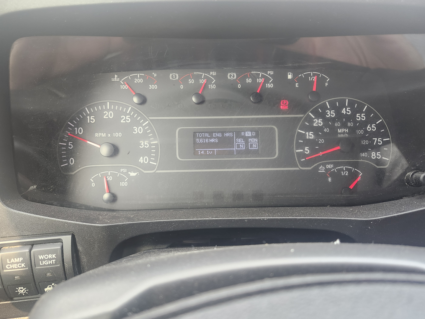 Dashboard view of a truck showing gauge cluster with RPM and speedometers, center digital display, warning lights, and various dials.