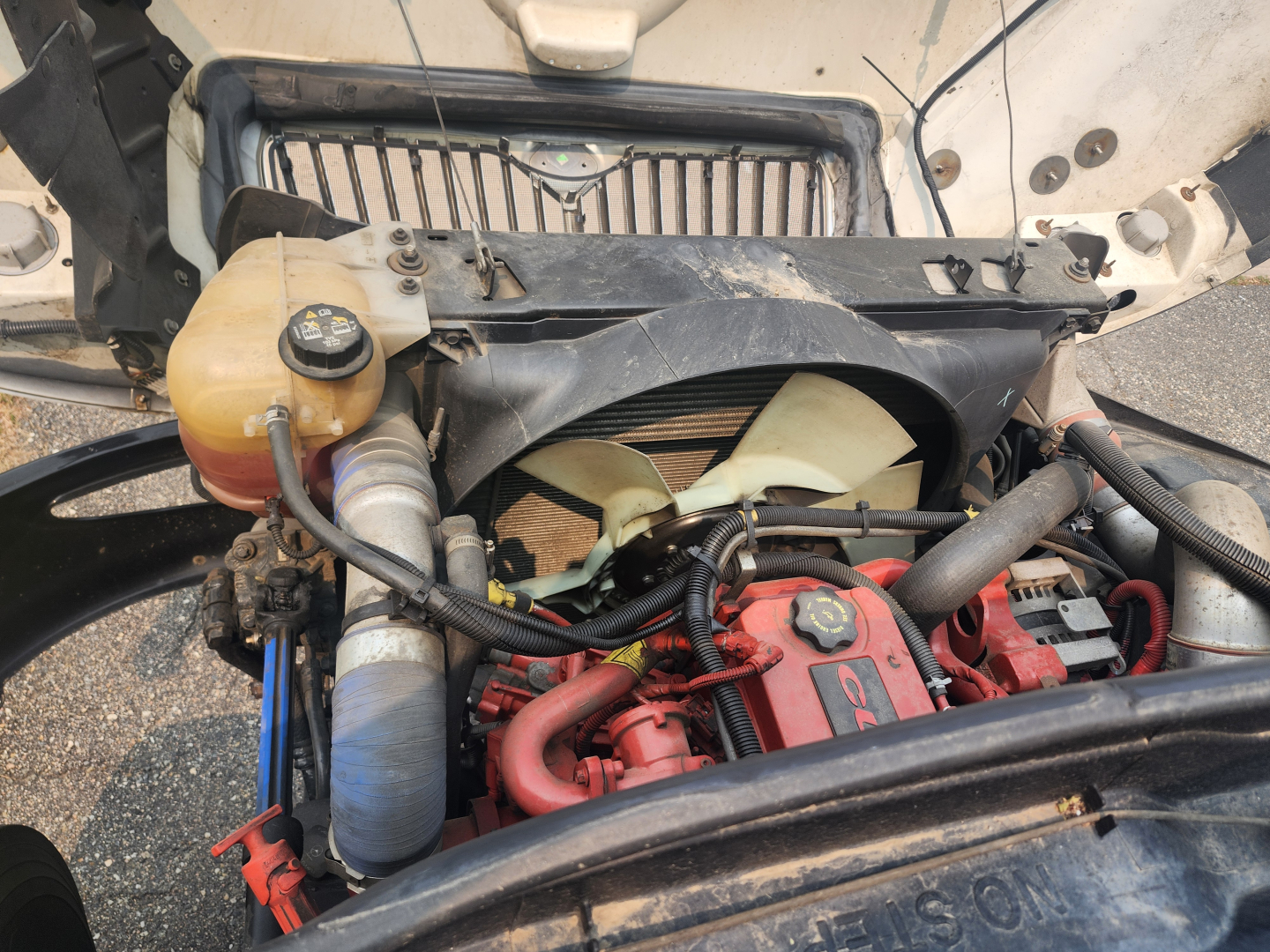 Engine bay of 2020 International MV607 with radiator, coolant reservoir, turbo/intercooler piping, and red-painted engine block.