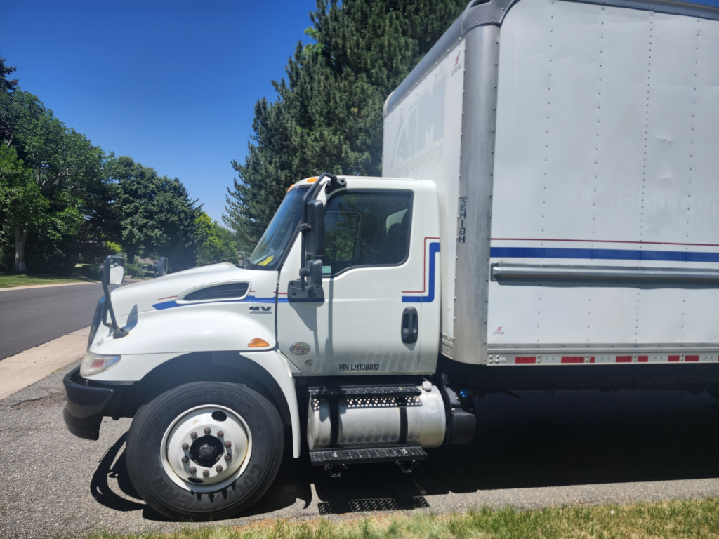 Truck cab and box trailer in service showing International MV series engine bay area and cargo box.