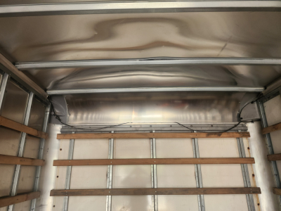 Interior of a box truck cargo area with wooden side rails and metal framing, empty cargo space.