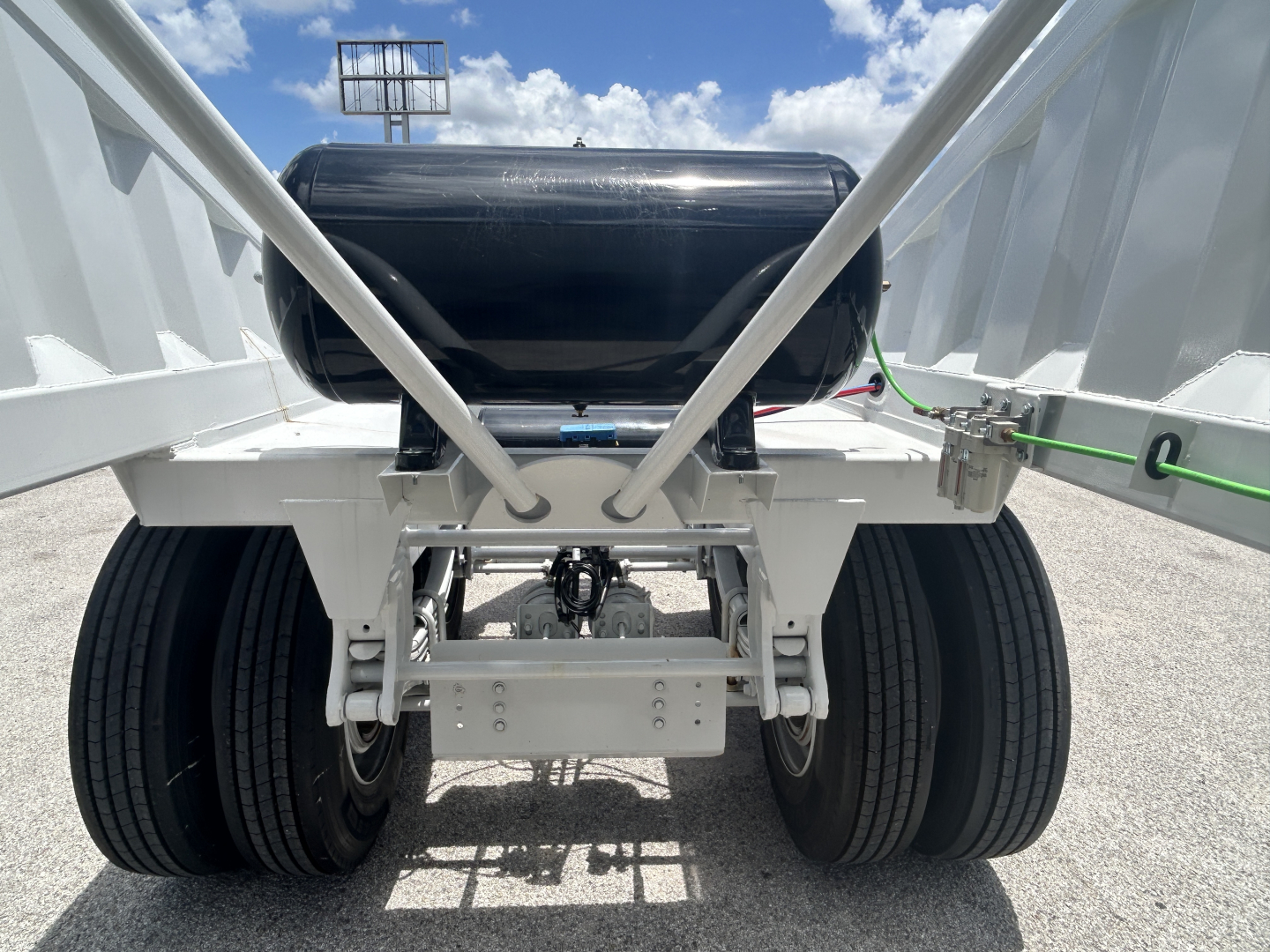 Trailer rear showing dual rear tires and black horizontal fuel tank with white chassis and linkage.
