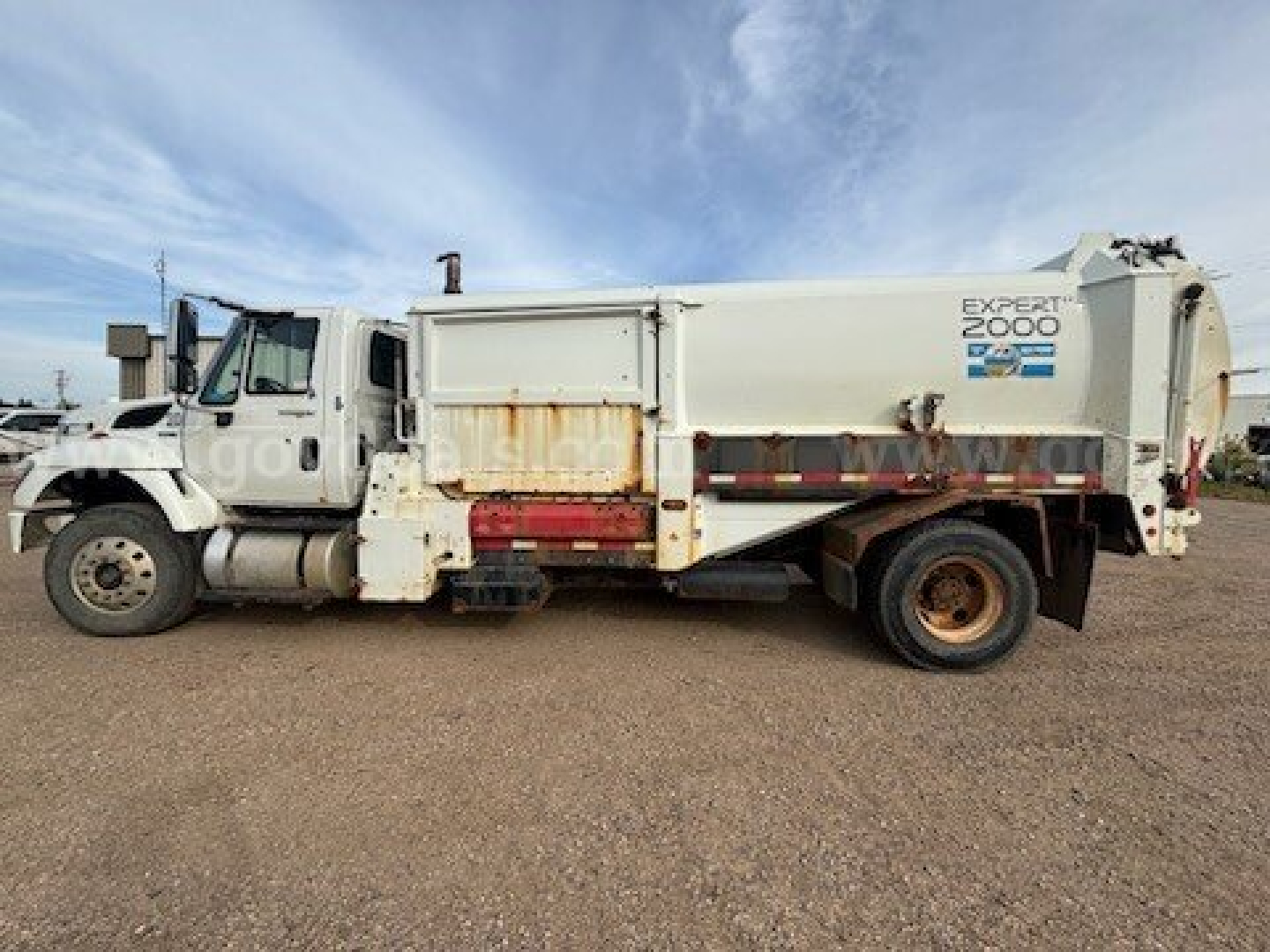 International 7400 garbage truck side view showing EXPERT 2000 body with aluminum hopper and rear compactor. 