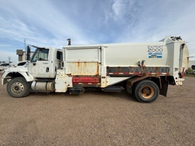 International 7400 garbage truck side view showing EXPERT 2000 body with aluminum hopper and rear compactor. 