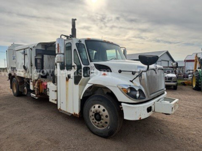 International 7400 dump truck in-service showing front-left side with white cab and dumping body.