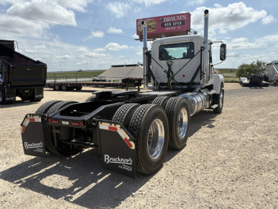 2027 Mack PI64T tractor with dual rear axles and fifth wheel showing rear mud flaps and tandem wheels in a gravel lot.