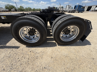 Dual rear tires on a Mack PI64T tractor chassis showing chrome wheels and tire treads with daytime sky in background.