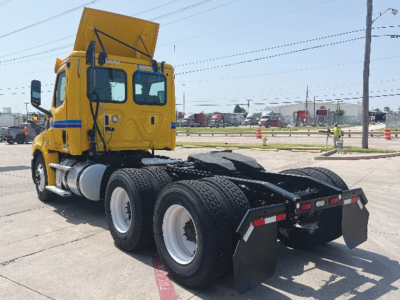 Freightliner Cascadia126 conventional daycab tractor rear view showing dual rear axles and fifth wheel hitch with yellow cab.