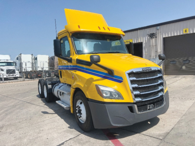 Truck cab showing bright yellow Freightliner Cascadia 126 with blue graphics and front grille.