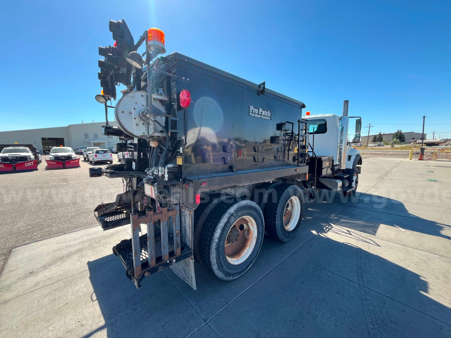 International WorkStar 7600 dump truck with black dump body, rear equipment, and orange beacon, side view showing dual rear wheels and hydraulic components.