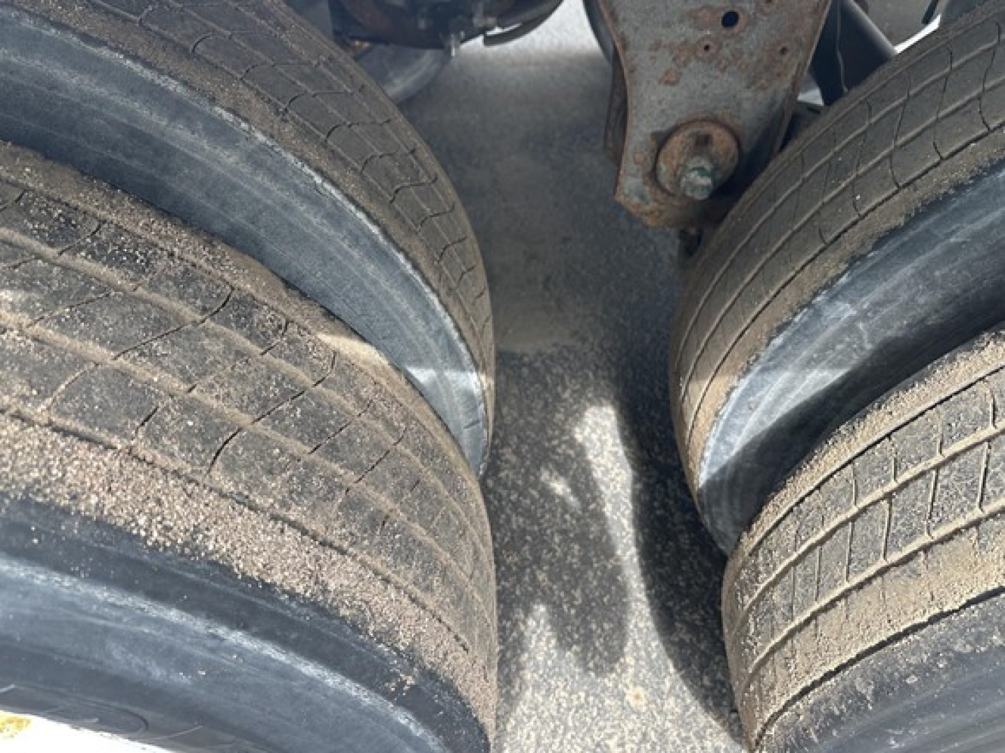 Trailer axle with dual tires and leaf spring mounting, worn tread on tires; view between front dual tires of a 2018 Utility 3000R trailer.