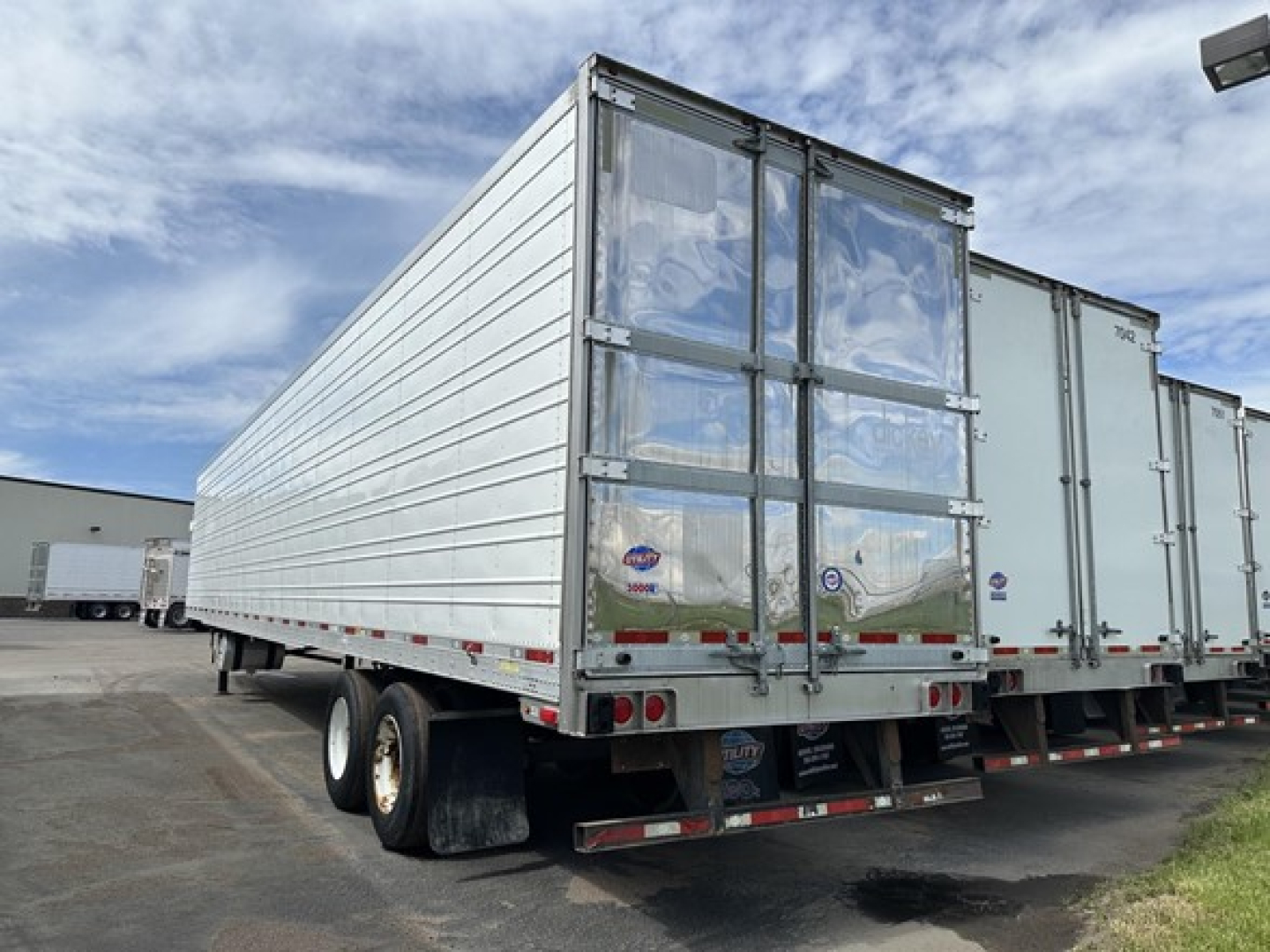 Utility 3000R trailer rear and side view showing aluminum panel body, double rear doors, dual rear tires, and taillights.