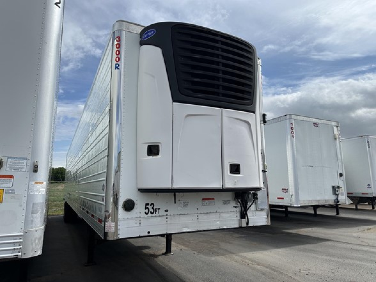 Utility reefer trailer with Thermo King unit on front, white exterior, vertical '3000R' branding near nose, 53,000 lb capacity markings, other trailers in background.