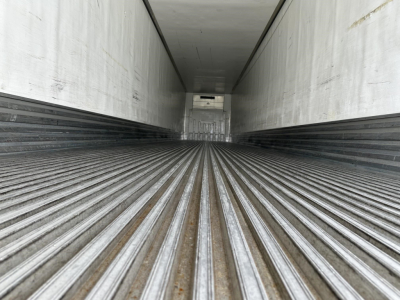 Trailer interior showing ribbed steel floor and white walls; perspective down length to the rear.