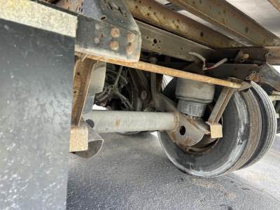 Trailer undercarriage with suspension and wheel assembly showing leaf springs and axle in service condition