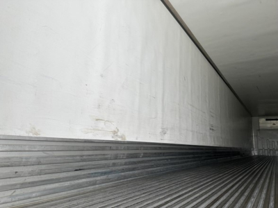 Utility trailer interior with ribbed floor and side walls; empty cargo area; aluminum interior panels; light entering from open end.