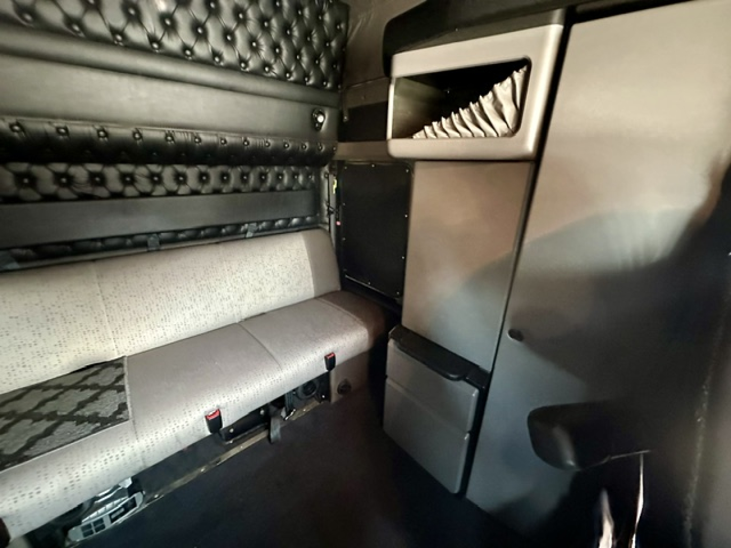 Kenworth W900L cab interior showing sleeper area and storage cabinets with upholstery and controls.