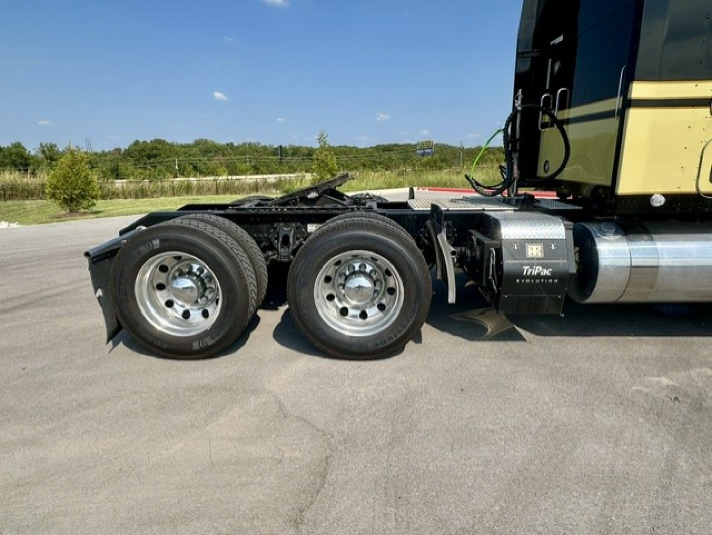 Kenworth W900L left-side rear view showing tandem axles and fuel tanks.