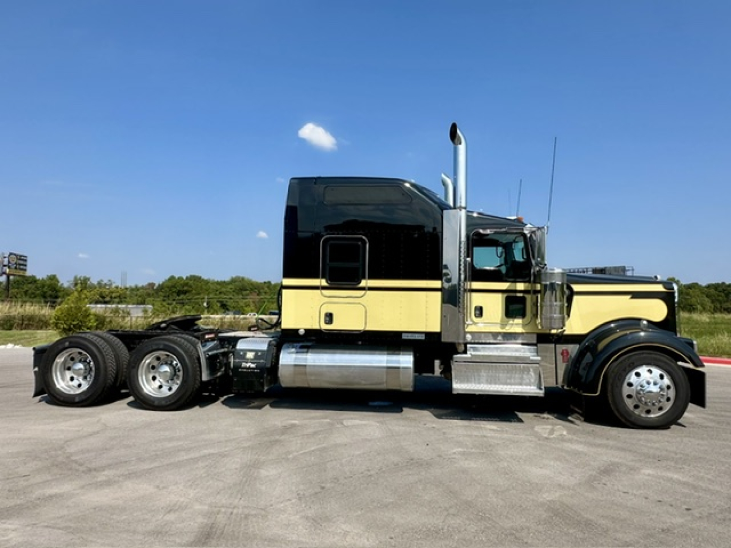 Kenworth W900L truck side view showing diesel fuel tank and chrome exhaust stack.