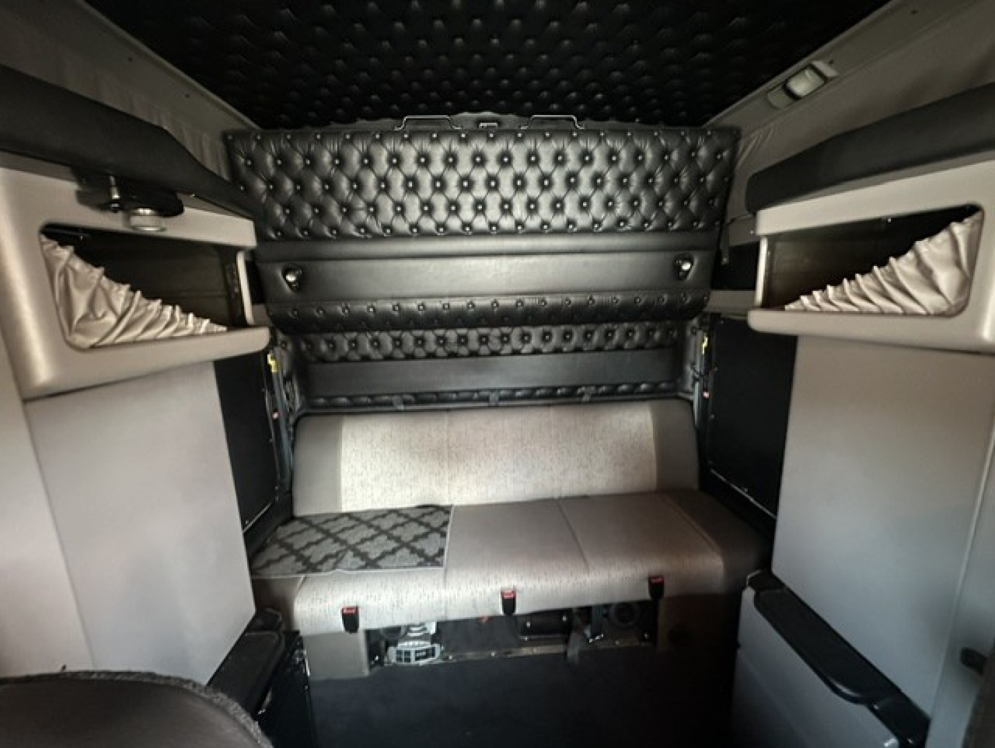 Interior sleeper cab of a 2023 Kenworth W900L showing upholstered bunk area and quilted headboard.