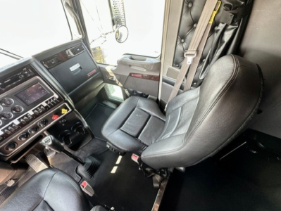 Truck cab interior showing driver seat and dashboard of a Kenworth W900L; visible controls and steering wheel, no specific text readable.