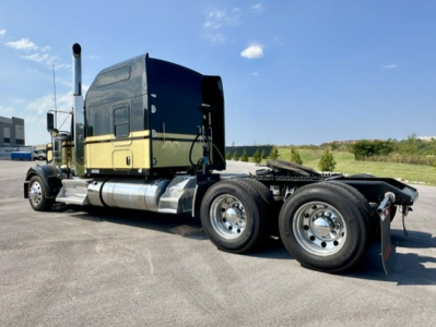 Kenworth W900L cab-over tractor chassis in profile view with dual rear axles, fuel tanks, and exhaust stacks visible.