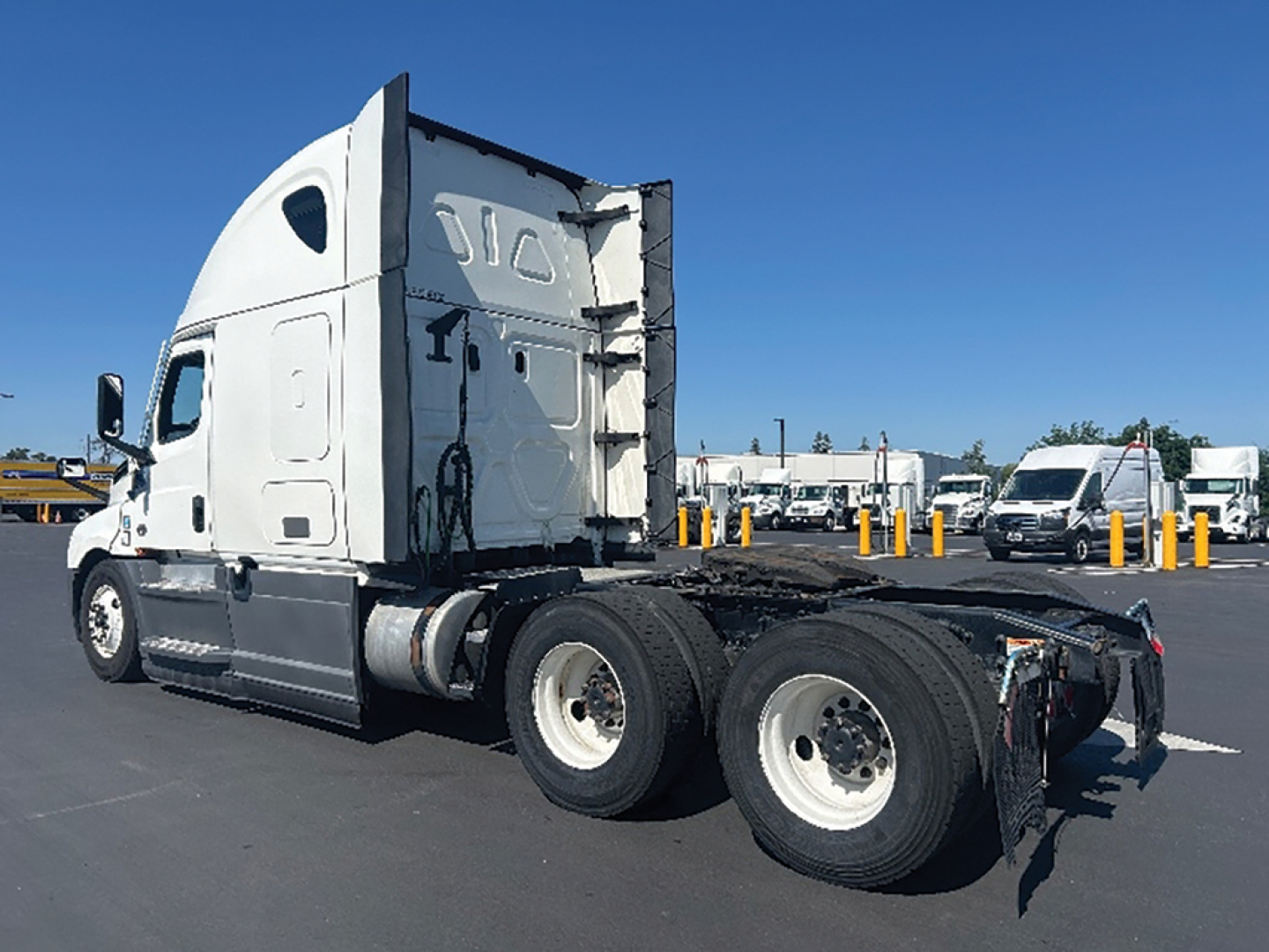 Truck chassis in profile view showing Freightliner Cascadia cab and triple rear axles without trailer.