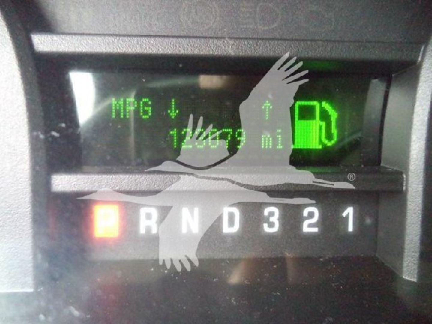 Dashboard showing gear selector with R N D 3 2 1 and fuel gauge, MPG indicator and odometer reading 1700? miles. Inset green digital display.