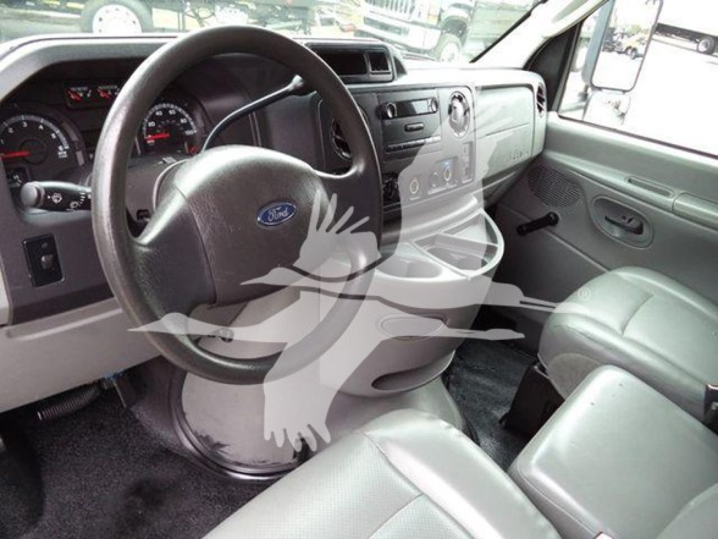 Ford E-Series interior showing steering wheel with Ford logo, dashboard, and front seats in a box truck cab.