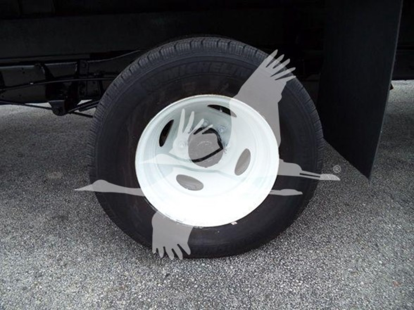 Wheel close-up on a Ford E-450 box truck showing a white steel wheel and tire mounted on a black undercarriage.